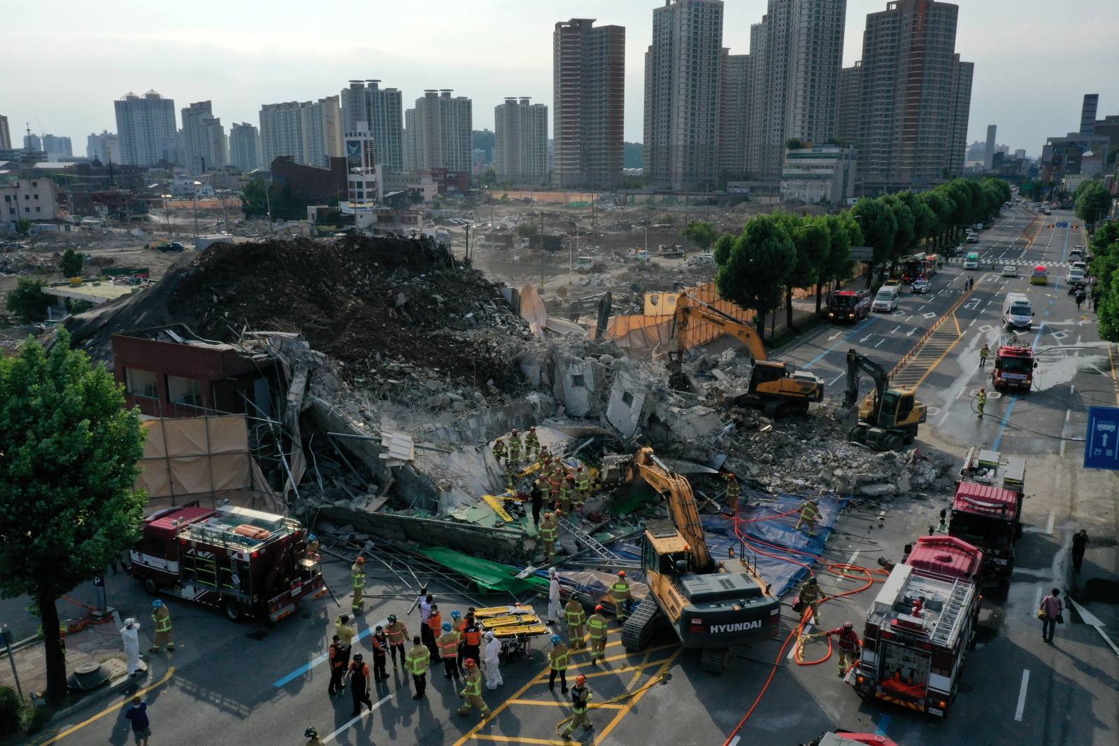 South Korean firefighters search for passengers from a bus trapped by the debris of a collapsed building in Gwangju