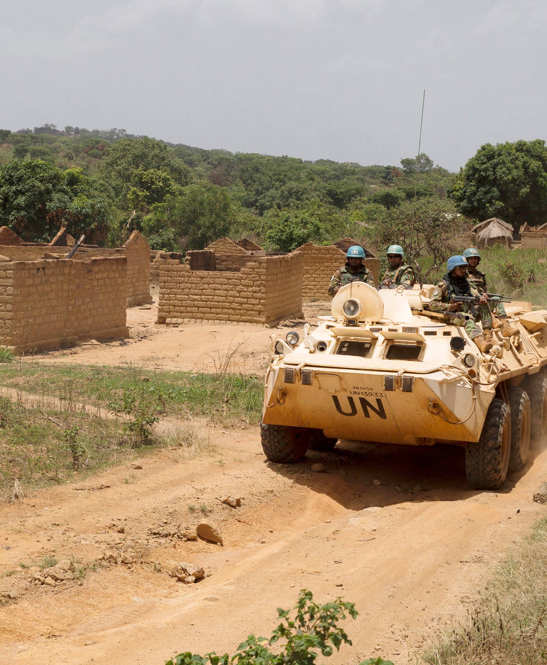 United Nations peacekeeping force vehicles drive by houses destroyed by violence in September, in the abandoned village of Yade, Central African Republic
