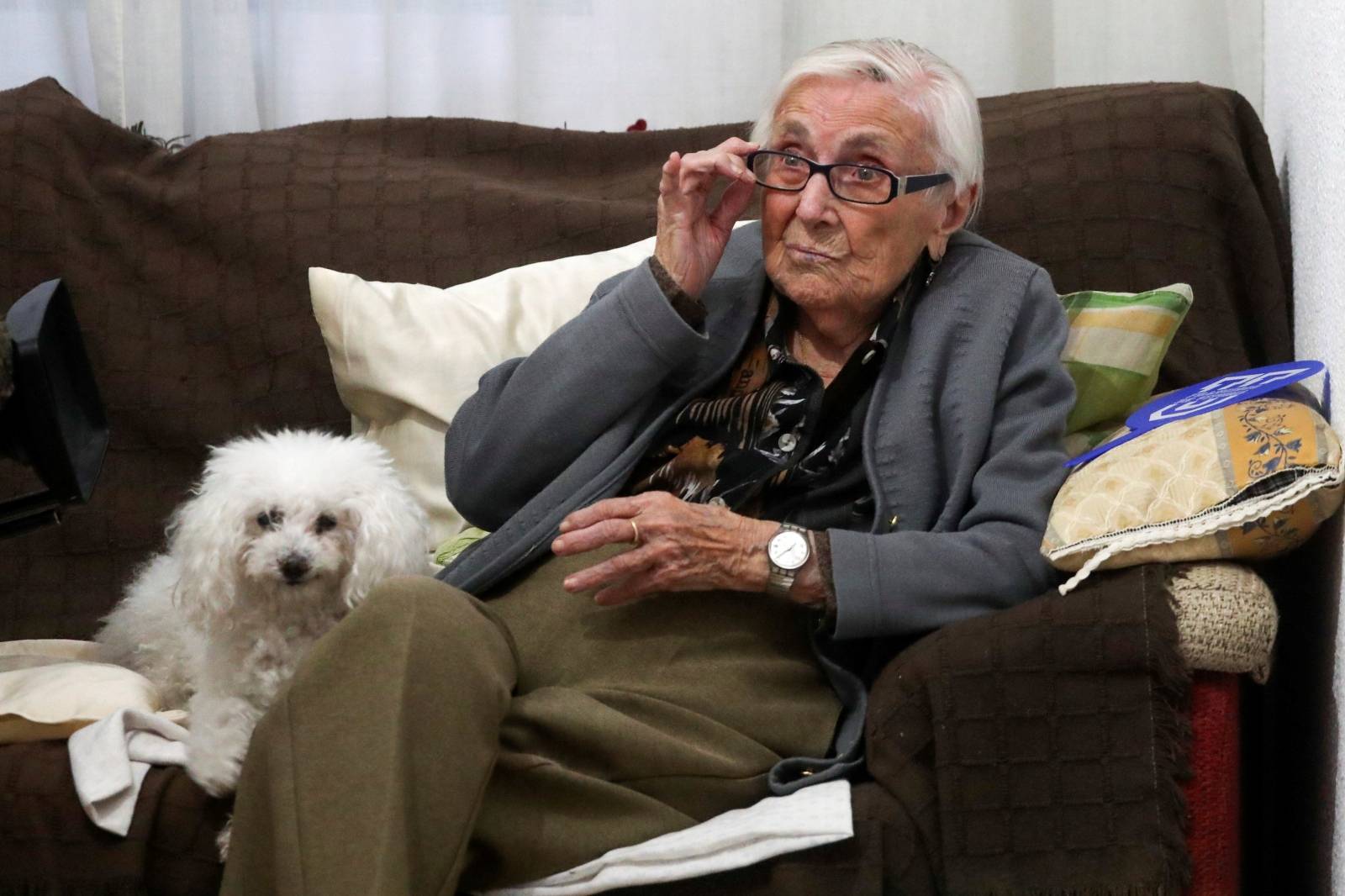Florentina Martin, a 99 year-old woman who survived coronavirus disease (COVID-19), sits on a sofa with her pet Luna as she watches TV in her home in Pinto