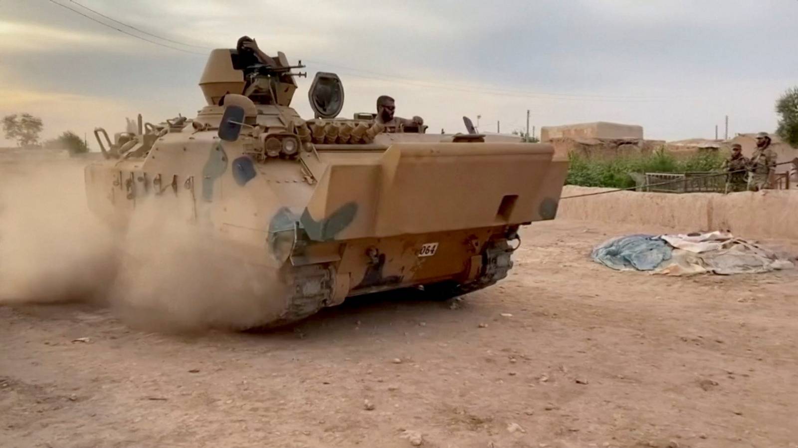 Still image from video shows Syrian rebel fighters driving a tank through a field near Tal Abyad