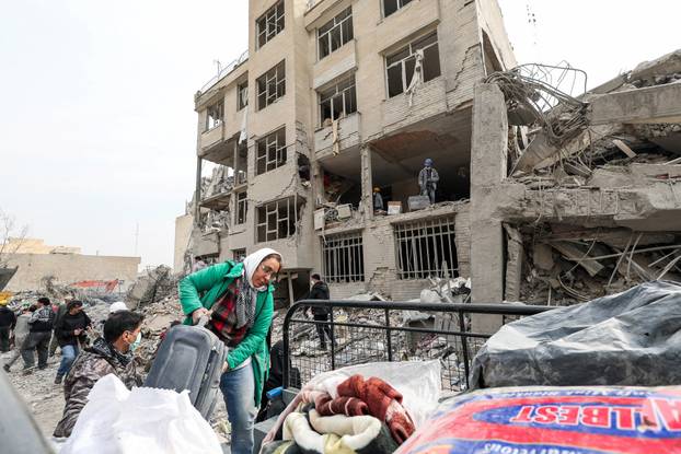 A family gathers the remaining furniture from an apartment damaged by an airstrike, in Tehran