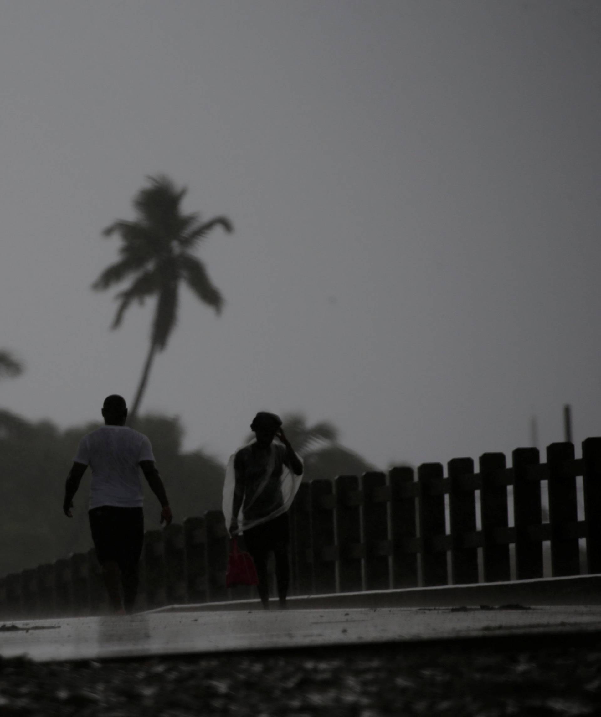 People walk across a bridge in the rain brought by Hurricane Irma in Cap-Haitien