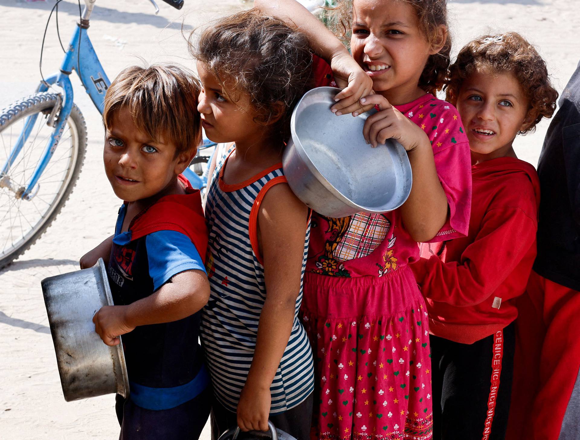 Palestinians gather to receive food cooked by a charity kitchen, in Khan Younis