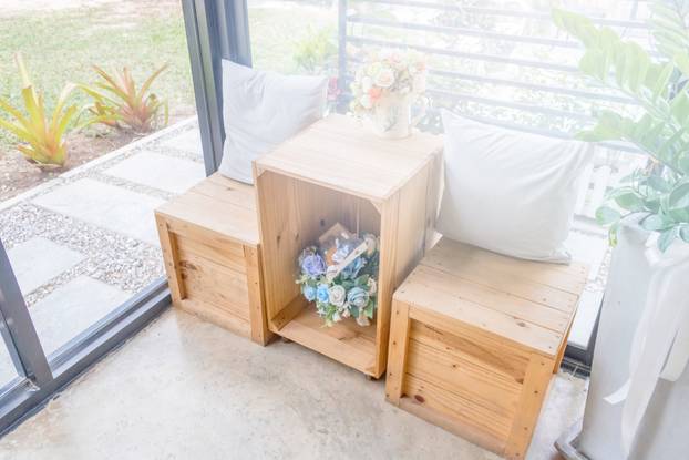 Two pillows on wooden desk with wooden stool and flower vases