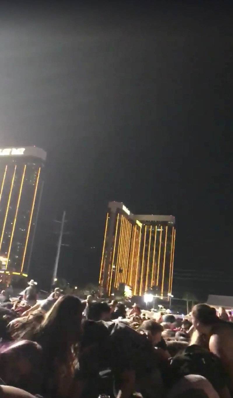 People attending the Route 91 Harvest Music Festival, crouch down as a gunman opens fire from the 32nd floor of a hotel, in Las Vegas
