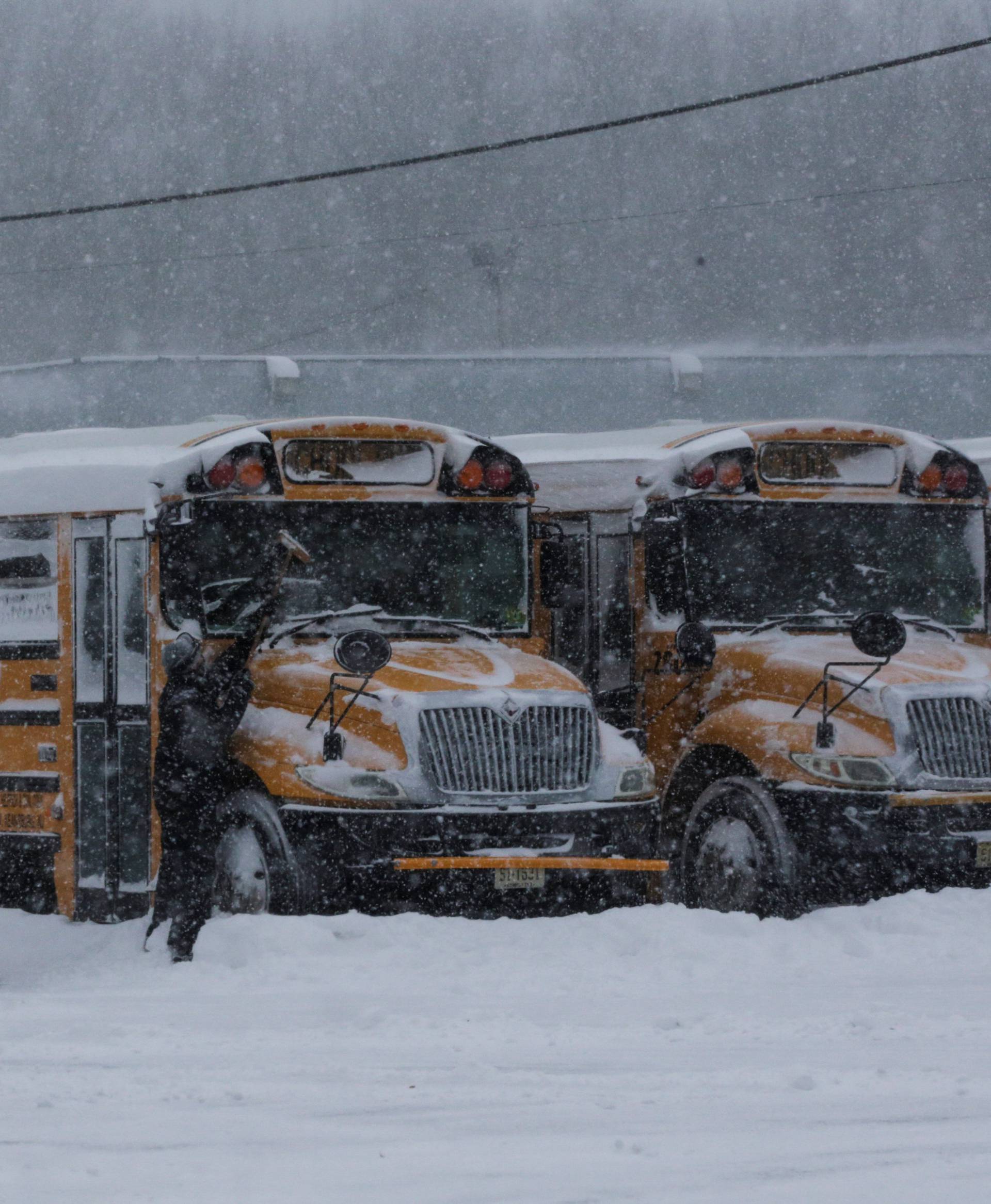 People clean school buses during Storm Grayson at the Jersey shore in Keansburg, New Jersey