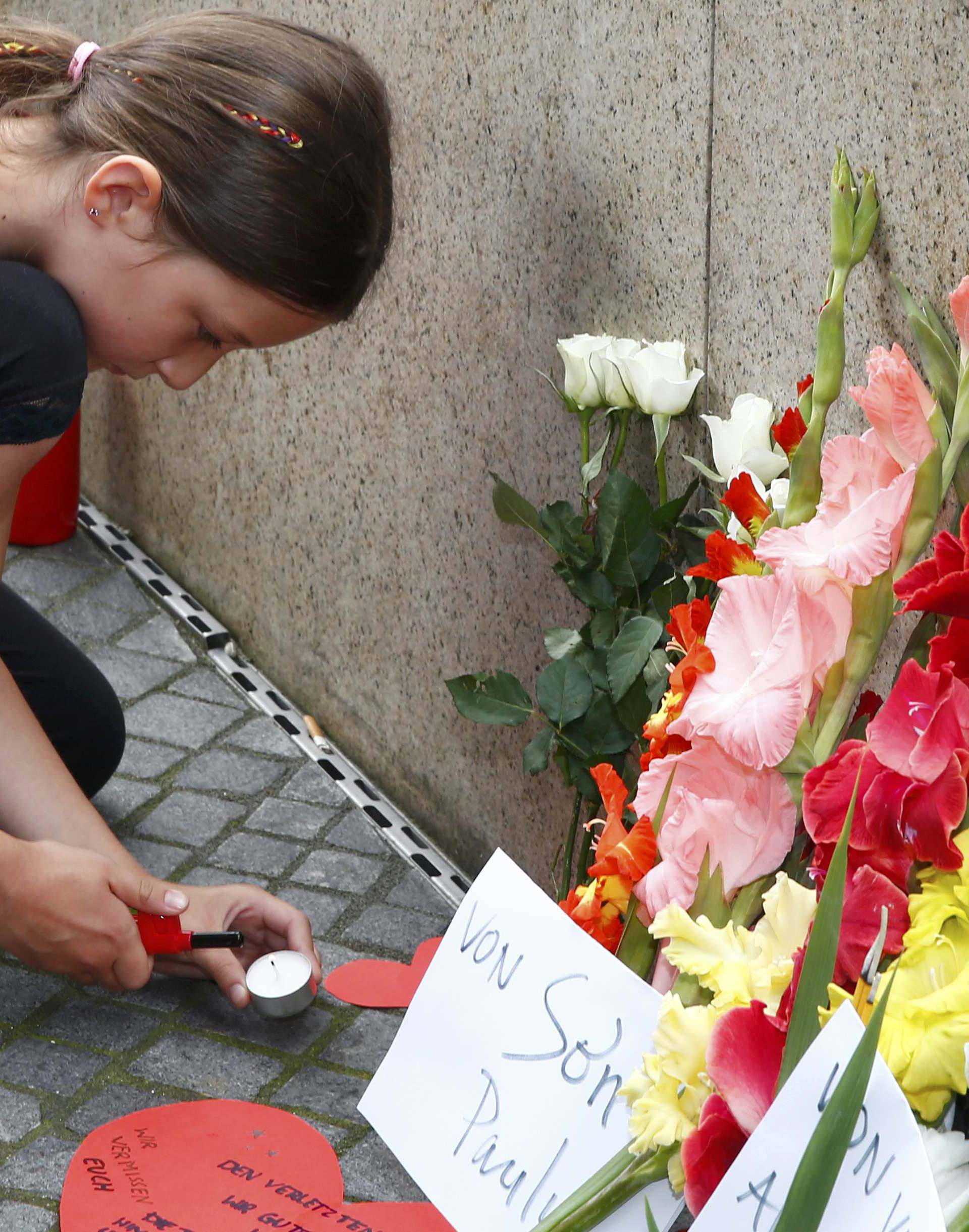 A young girl lights a candle near Olympia shopping mall in Munich