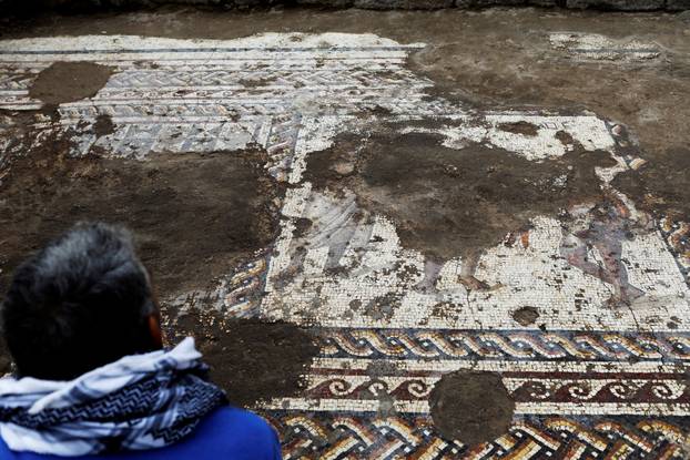 An Israel Antiquities Authority worker looks at a mosaic floor decorated with figures, which archaeologists say is 1,800 years old and was unearthed during an excavation in Caesarea