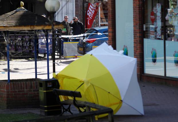 Local officials survey the scene as the forensic tent, covering the bench where Sergei Skripal and his daughter Yulia were found, is blown out of position in the centre of Salisbury