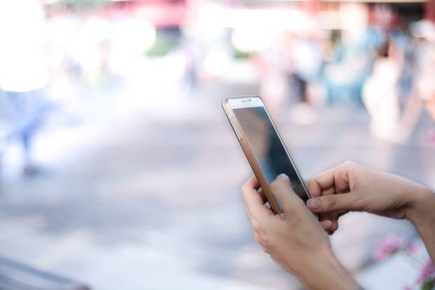 Mobile phone in Asian girl's hand with blur background.