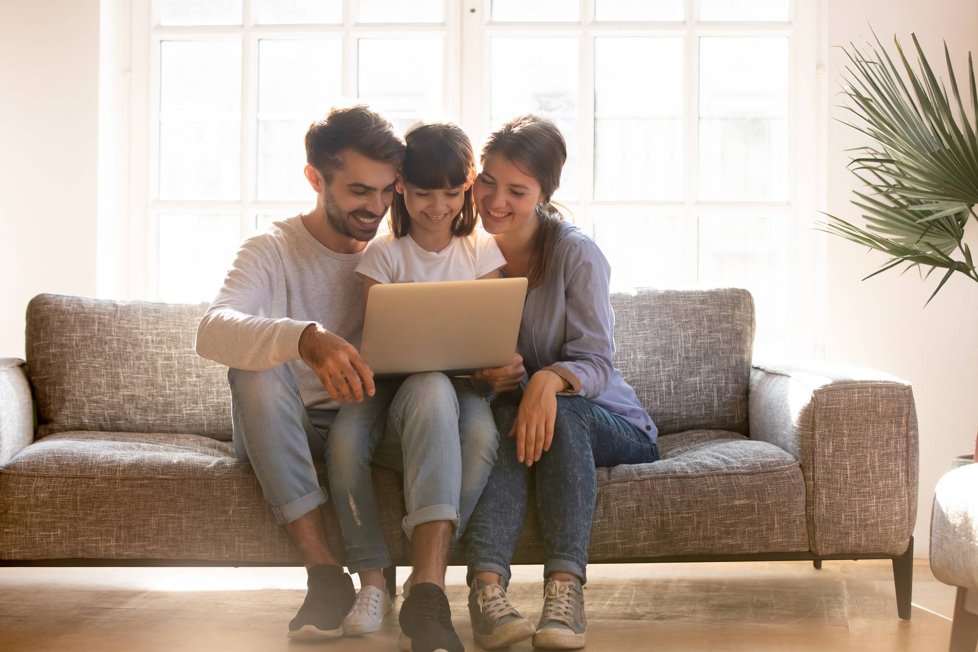 Happy family with kid using laptop together on sofa