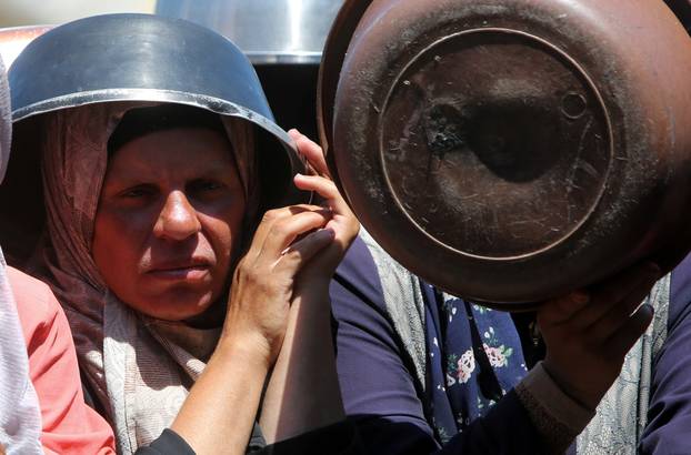 Palestinians wait to receive food from a charity kitchen, amid a hunger crisis, in Khan Younis