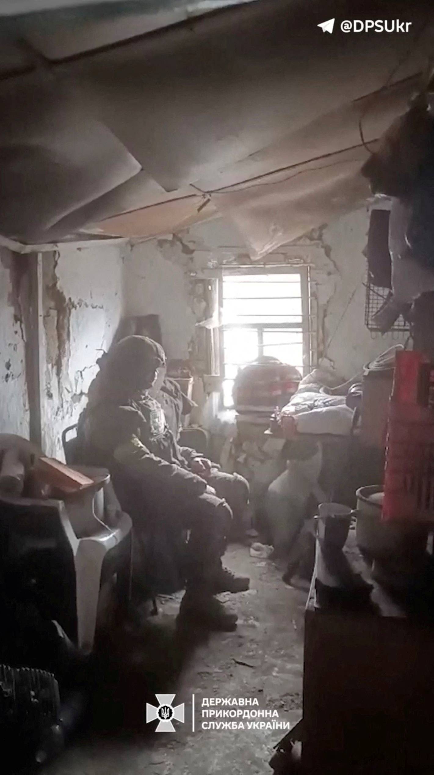 A Ukrainian soldier sits in a nearly destroyed room, in Avdiivka