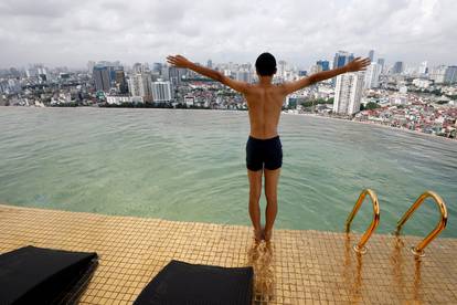 A boy jumps into the water at the gold-plated infinity pool of the newly inaugurated Dolce Hanoi Golden Lake luxury hotel in Hanoi