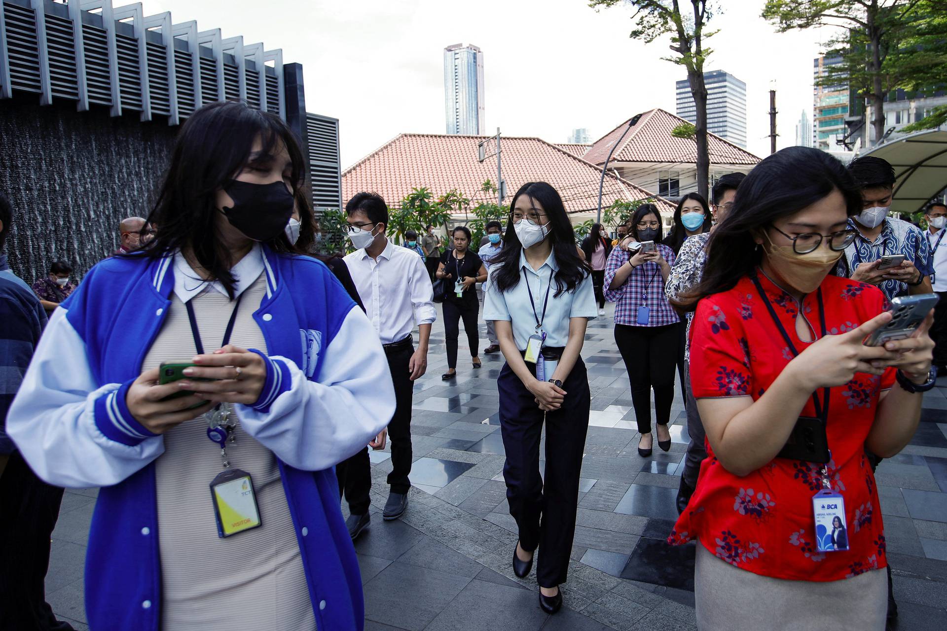 People gather as they are evacuated outside a building following an earthquake in Jakarta