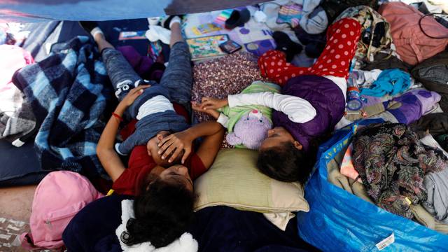 Children travelling with a caravan of migrants from Central America rest under a plastic tarp at a camp near the San Ysidro checkpoint, in Tijuana