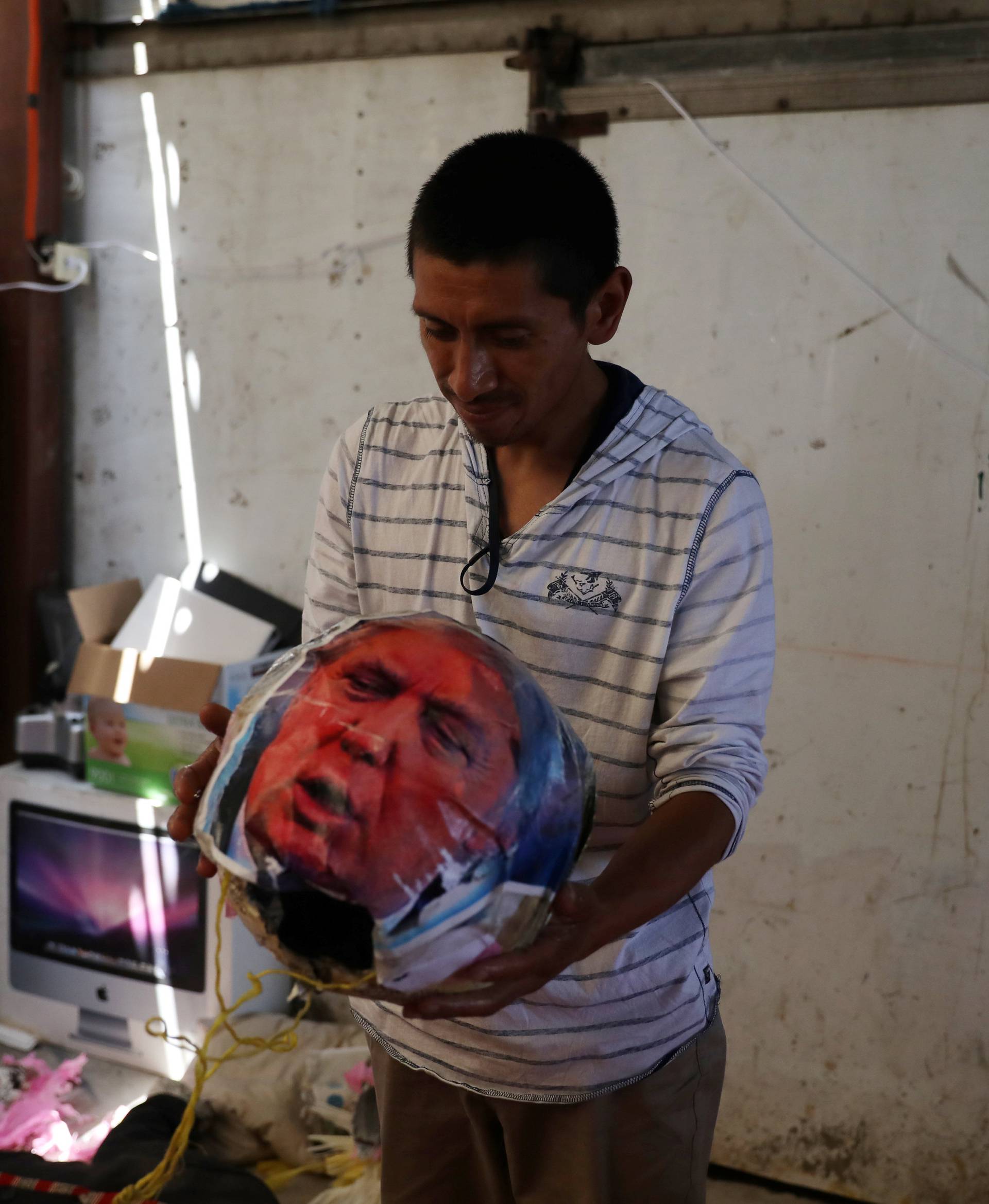 An activist makes the head of a puppet that mocks U.S. President Donald Trump at a migrant shelter in Tijuana