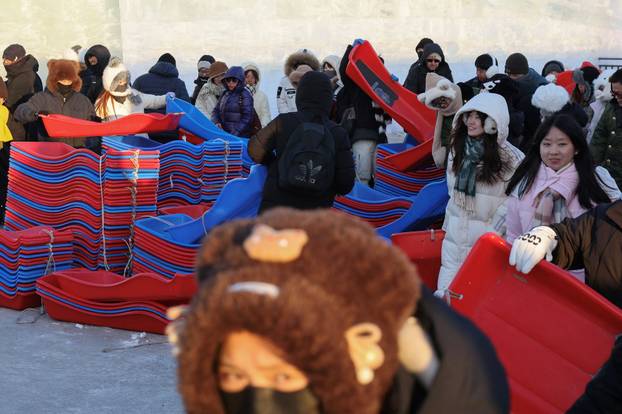 People pick up sleighs for the giant ice slides at the annual Ice and Snow Festival in Harbin