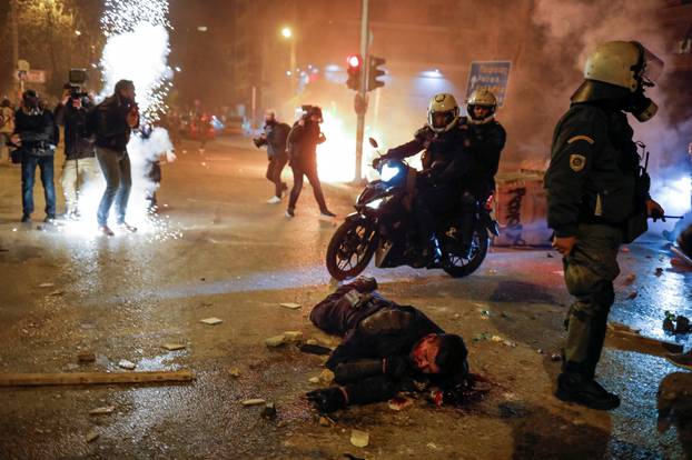 An injured police officer lies in the street during a demonstration in Athens