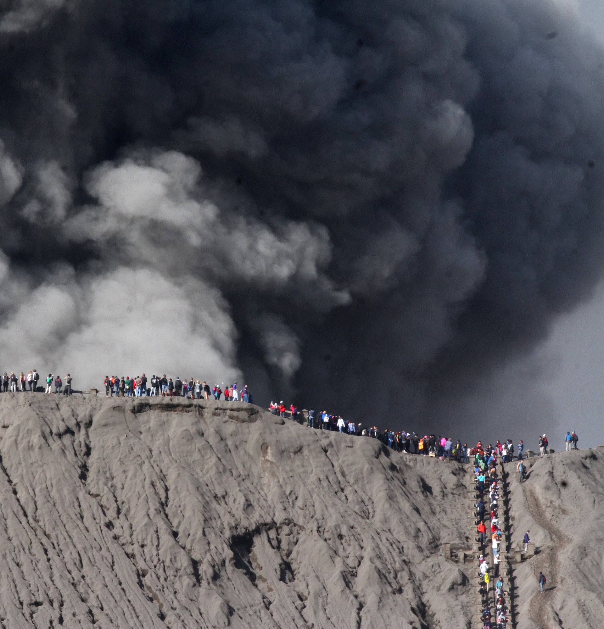 People standing on the edge of the crater while watching the eruption of Mount Bromo in Probolinggo