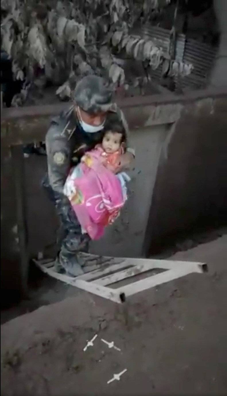 A soldier rescues a girl from a hole in an area affected by the eruption of Fuego volcano in Escuintla