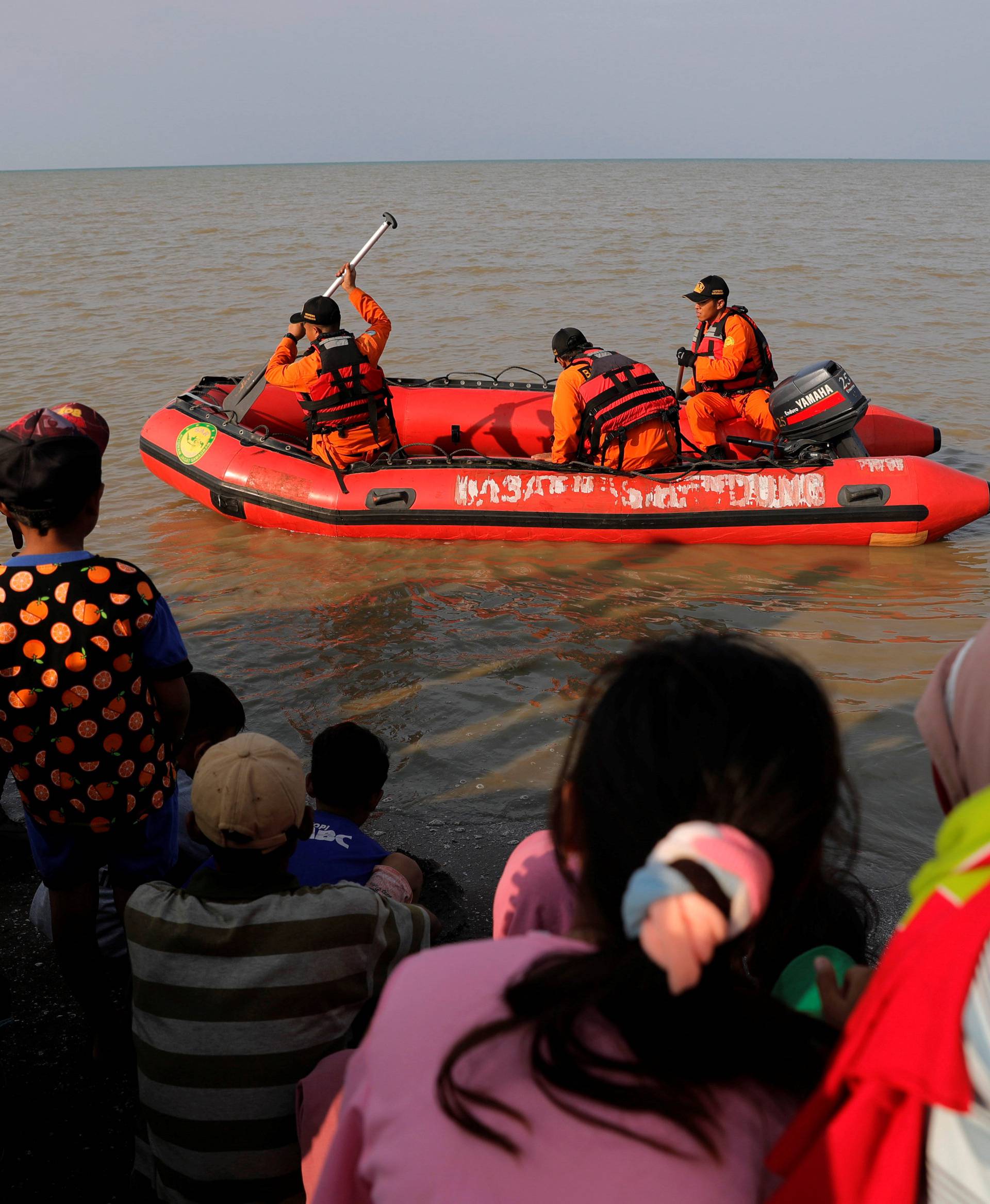 People watch rescue team members prepare the boat heading to the Lion Air, flight JT610, sea crash site off the coast of Karawang regency