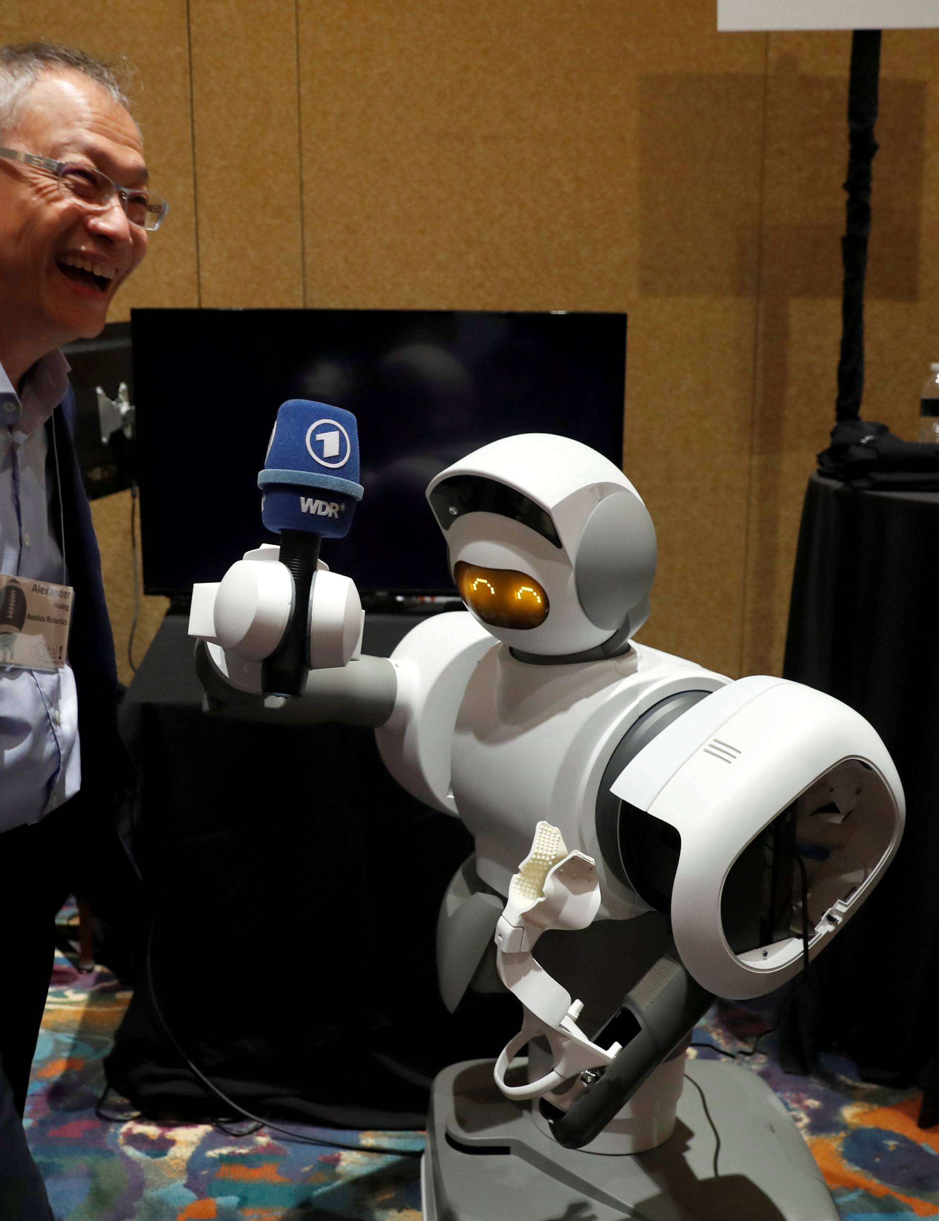 A home assistant robot holds a microphone for Alexander Huang, founder and CEO of Aeolus Robotics during Pepcom's Digital Experience in Las Vegas