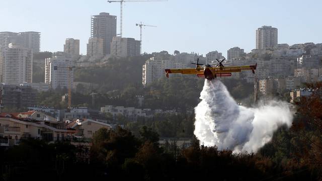A firefighting plane drops fire retardant during wildfire over the northern city of Haifa