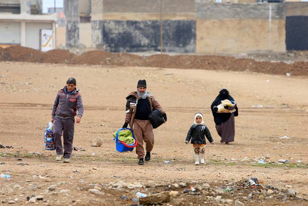 Displaced people, who are fleeing from Islamic State militants, carry their belongings as they walk in Mosul