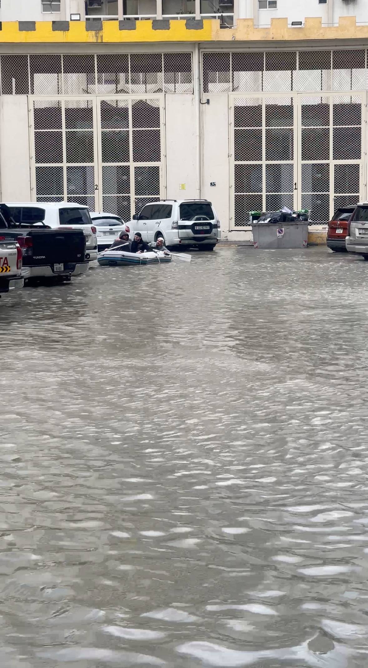 A group of men sail on a boat on a flooded street, in Dubai