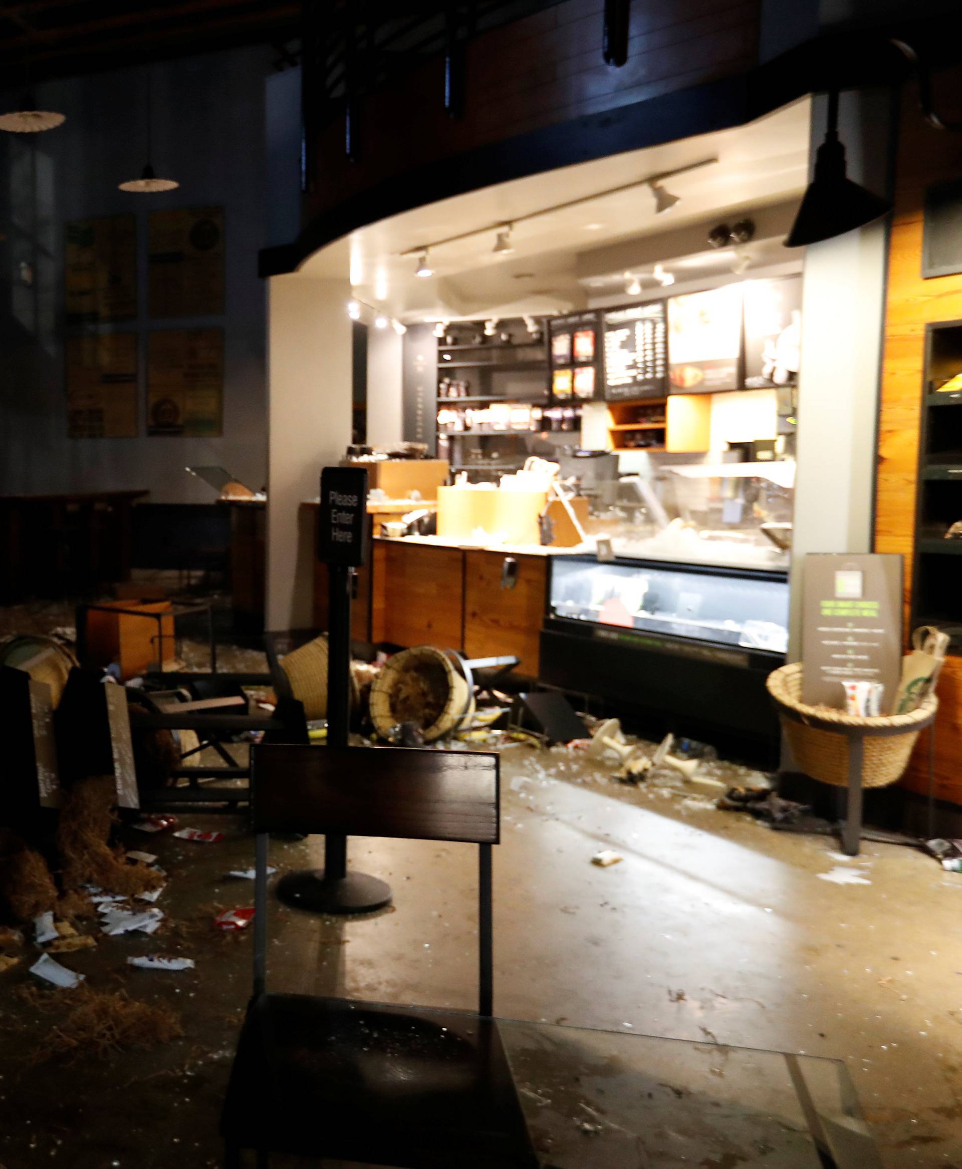 A worker surveys the damage to a vandalized Starbucks after a student protest turned violent at UC Berkeley during a demonstration over right-wing speaker Milo Yiannopoulos, who was forced to cancel his talk, in Berkeley, California