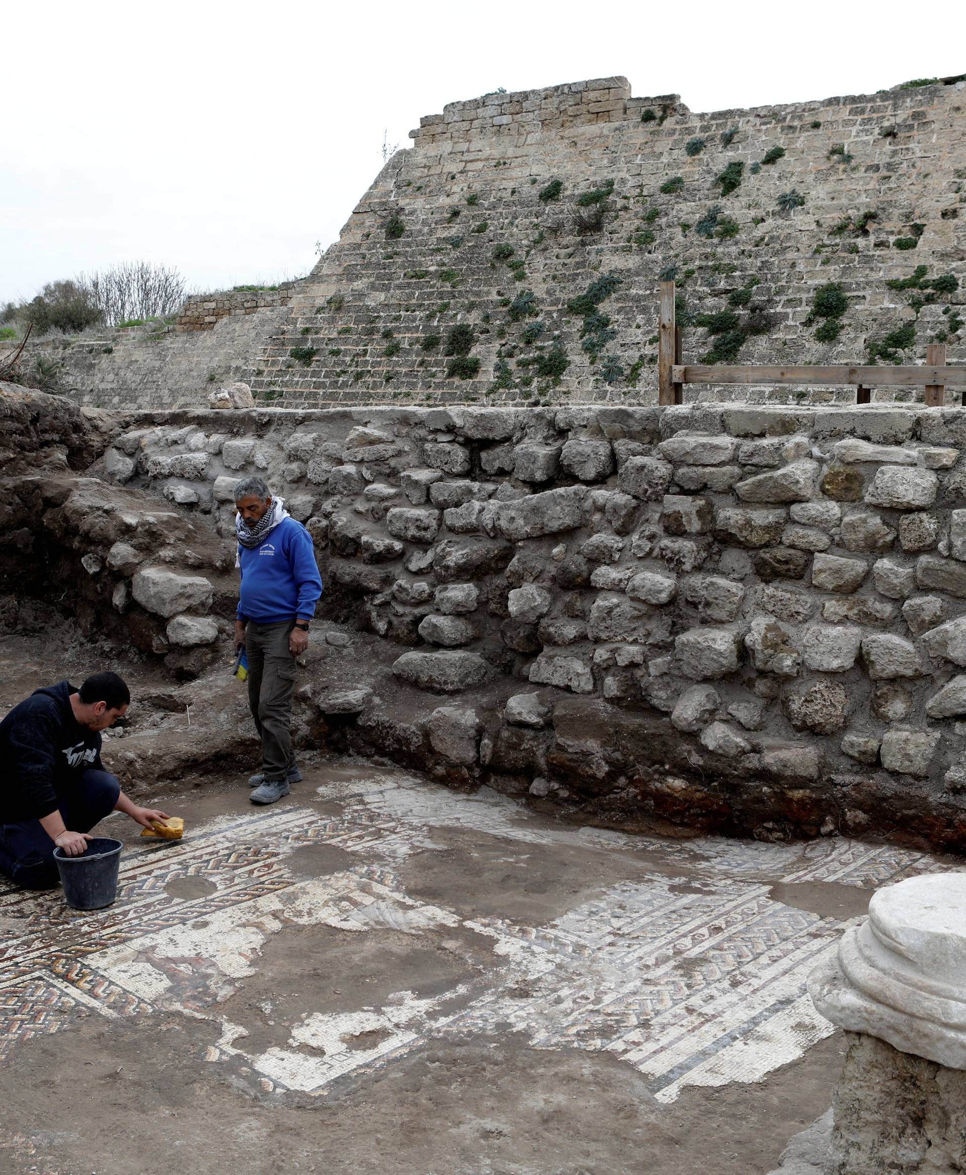 Israel Antiquities Authority workers clean a mosaic floor decorated with figures, which archaeologists say is 1,800 years old and was unearthed during an excavation in Caesarea