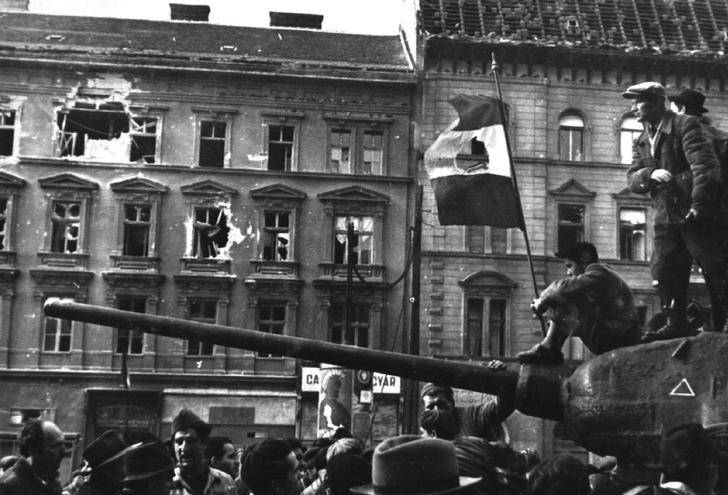 Fighters sit on top of a tank with a revolutionary flag in Budapest at the time of the uprising against the Soviet-supported Hungarian communist regime in 1956