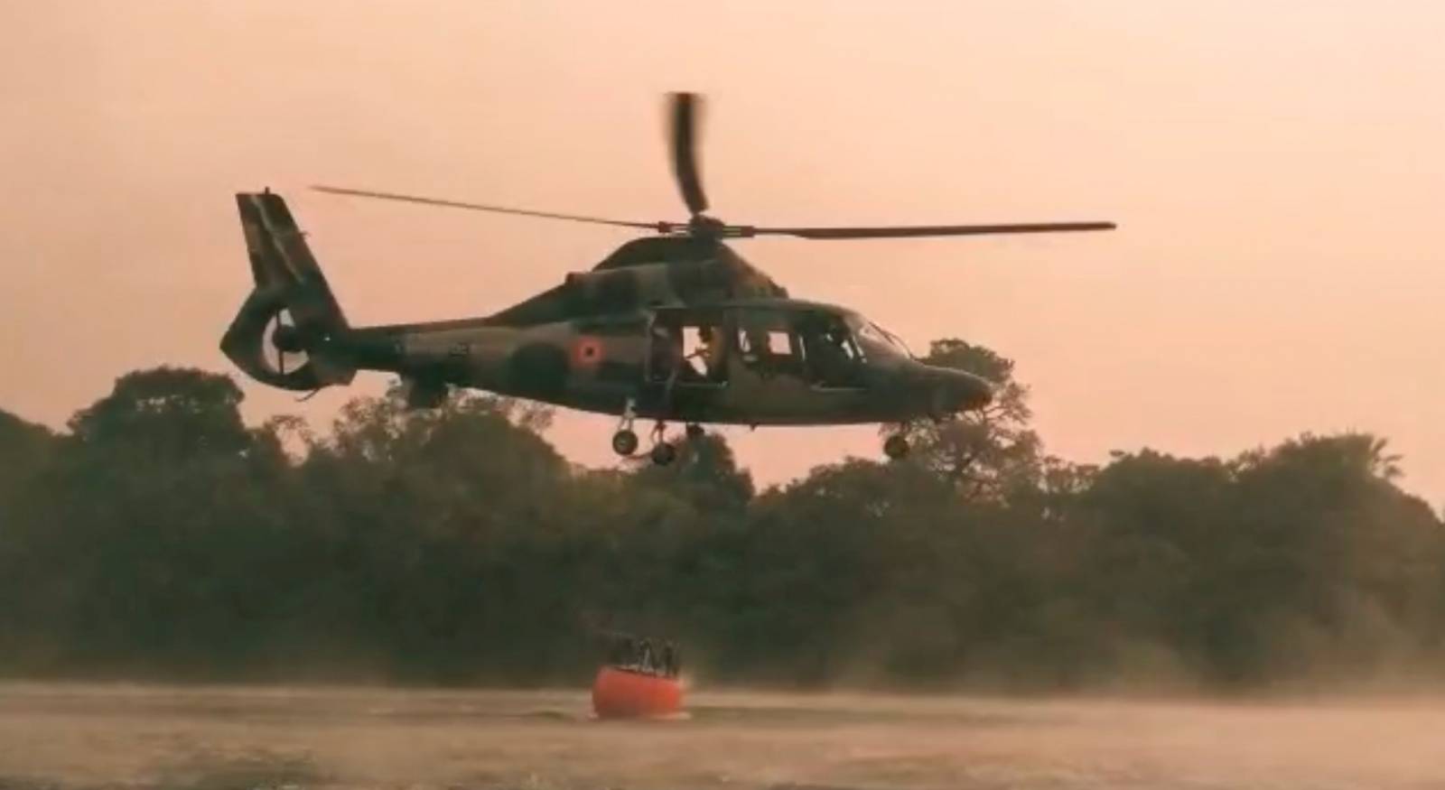 A Bolivian Air Force helicopter collects water to fight forest fire, near Robore