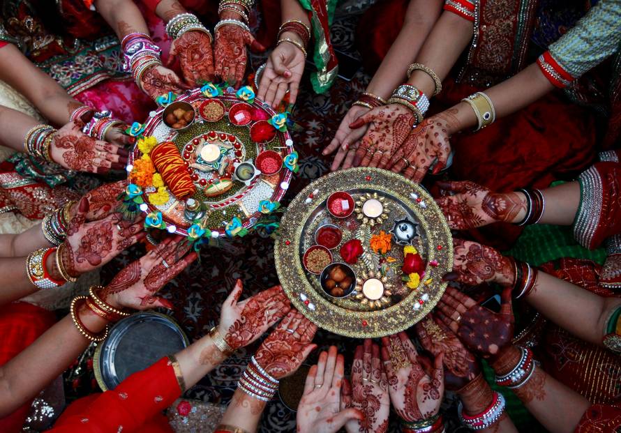 Married women pose for pictures as they perform rituals for the well being of their husbands during the Hindu festival of Karva Chauth in Ahmedabad