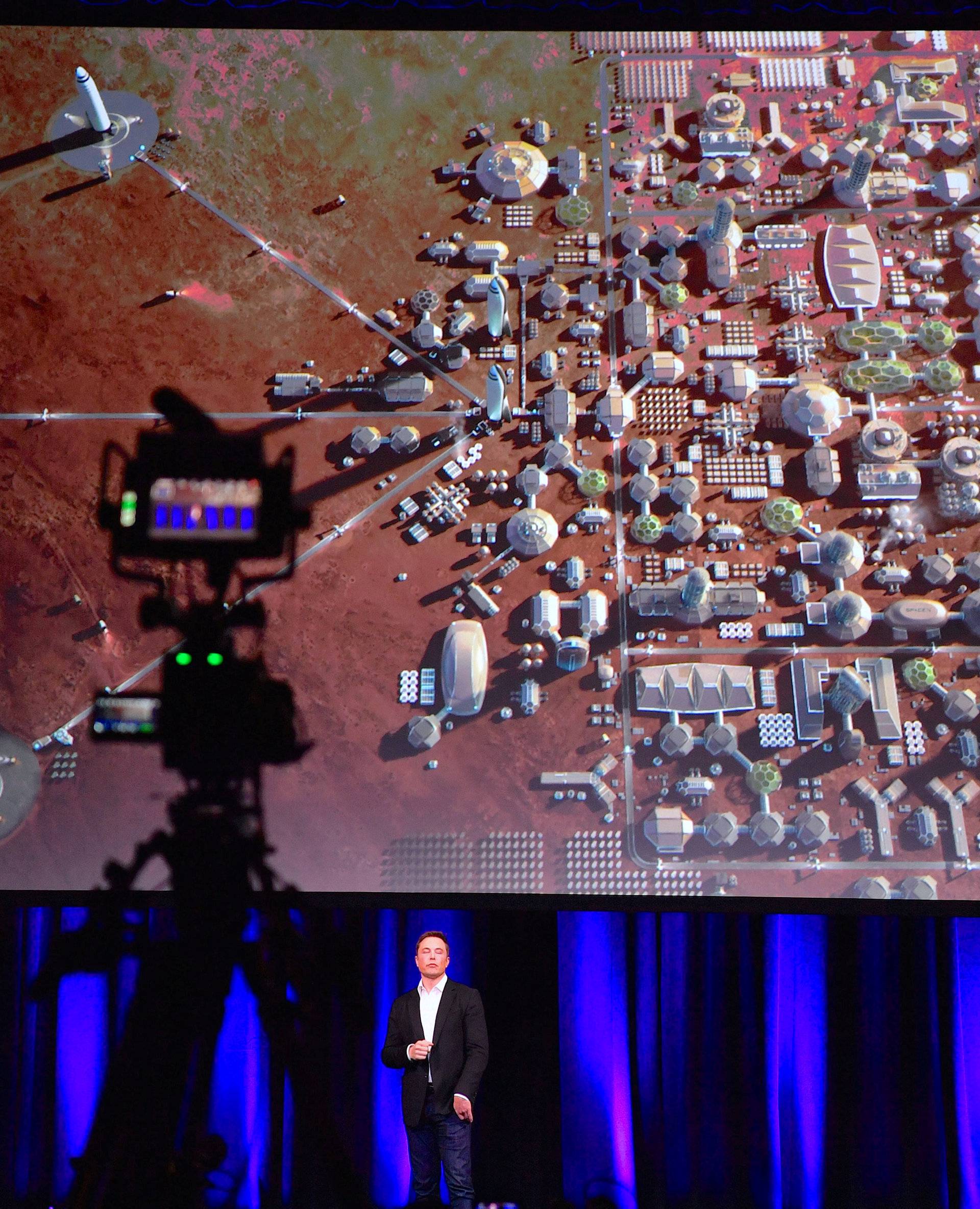 Elon Musk, founder and Chief Executive Officer and lead designer of SpaceX, reacts as a screen displays a depiction of a human colony on the planet Mars during a presentation at the International Astronautical Congress in Adelaide