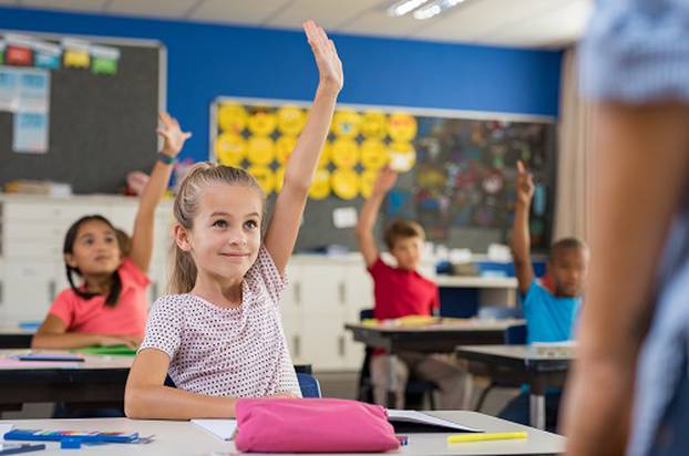 Children raising hands in classroom