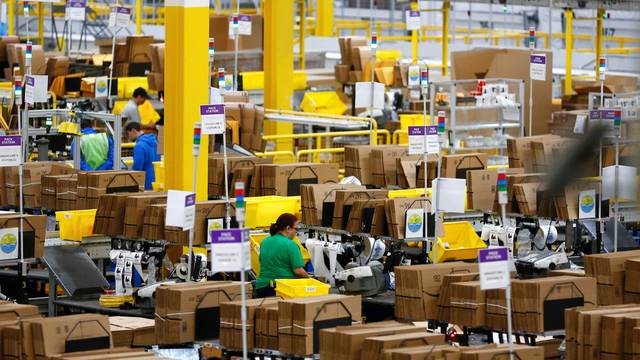 Employees work at pack stations at the Amazon fulfillment center in Kent