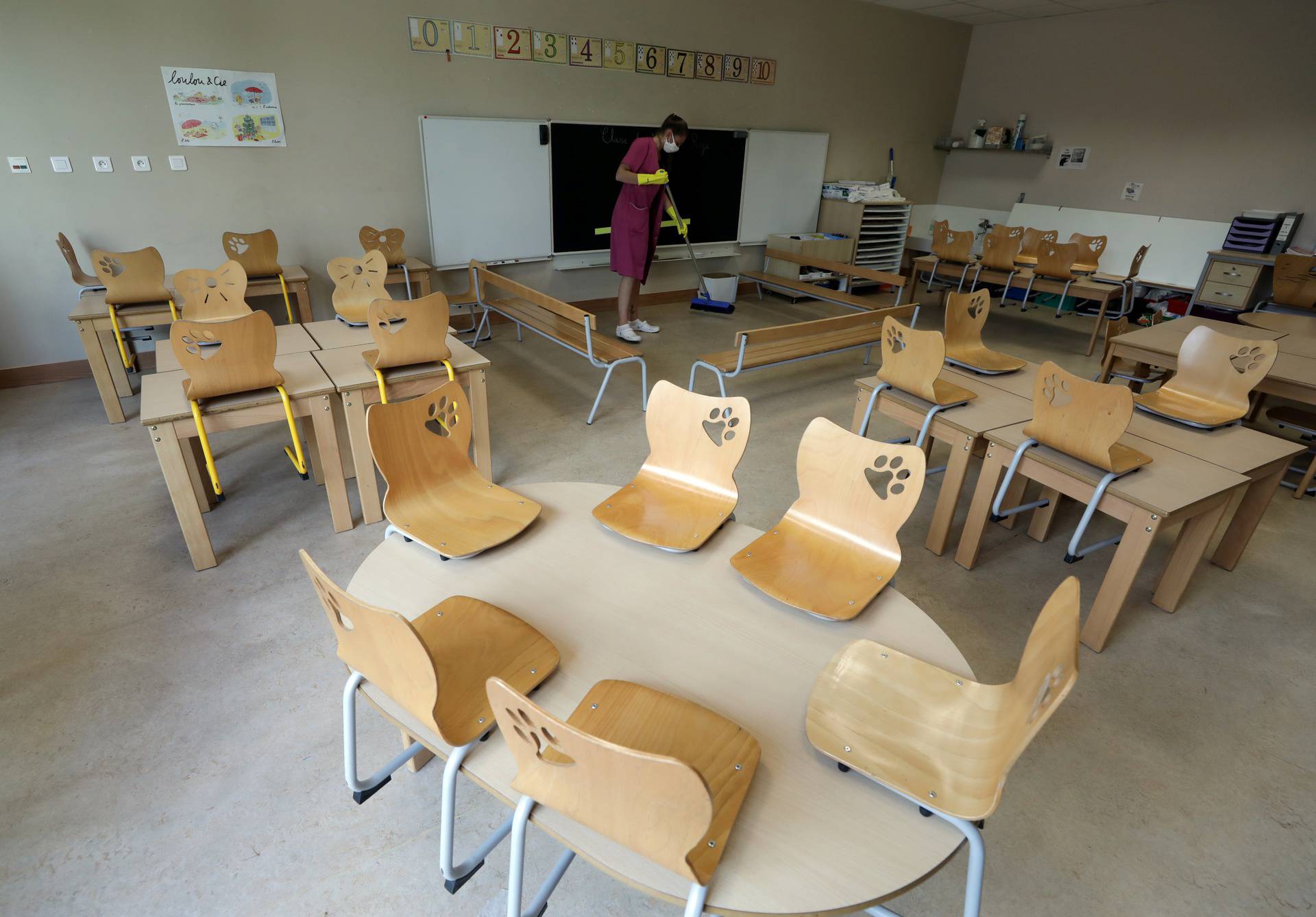 A municipal employee, wearing a protective face mask, cleans a classroom at a primary school in Le Cannet