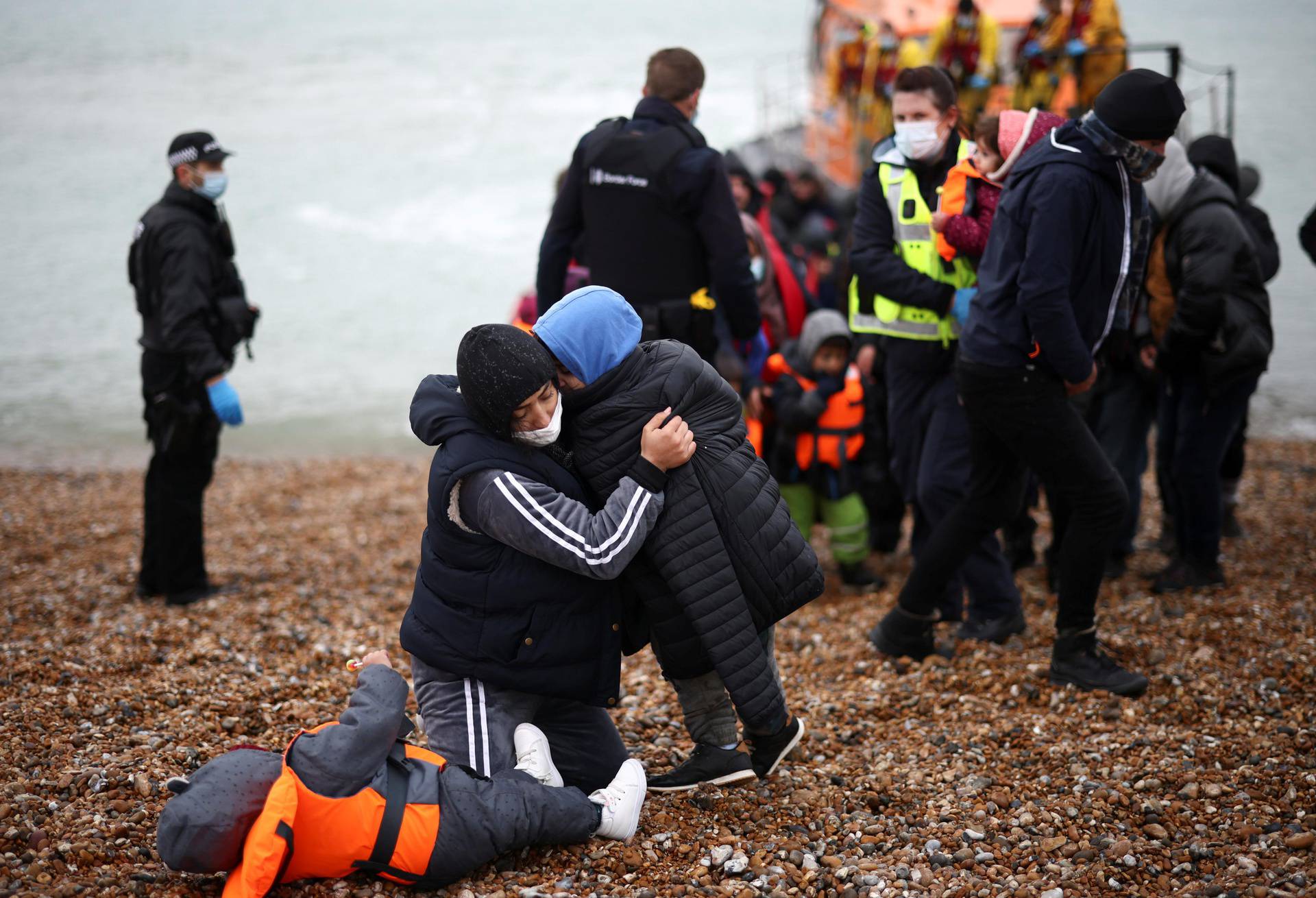 Migrants are brought ashore by RNLI Lifeboat staff, police officers and Border Force staff, after having crossed the channel, in Dungeness