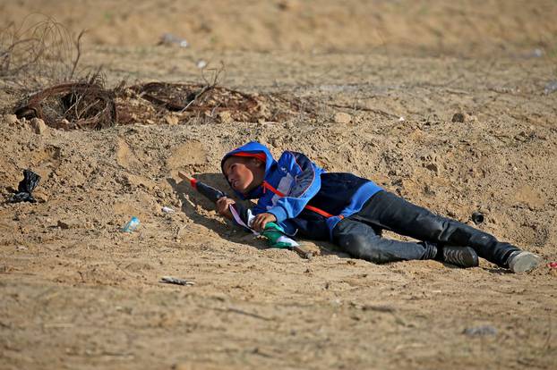 Palestinian boy takes cover from Israeli fire during an anti-Israel protest in the southern Gaza Strip
