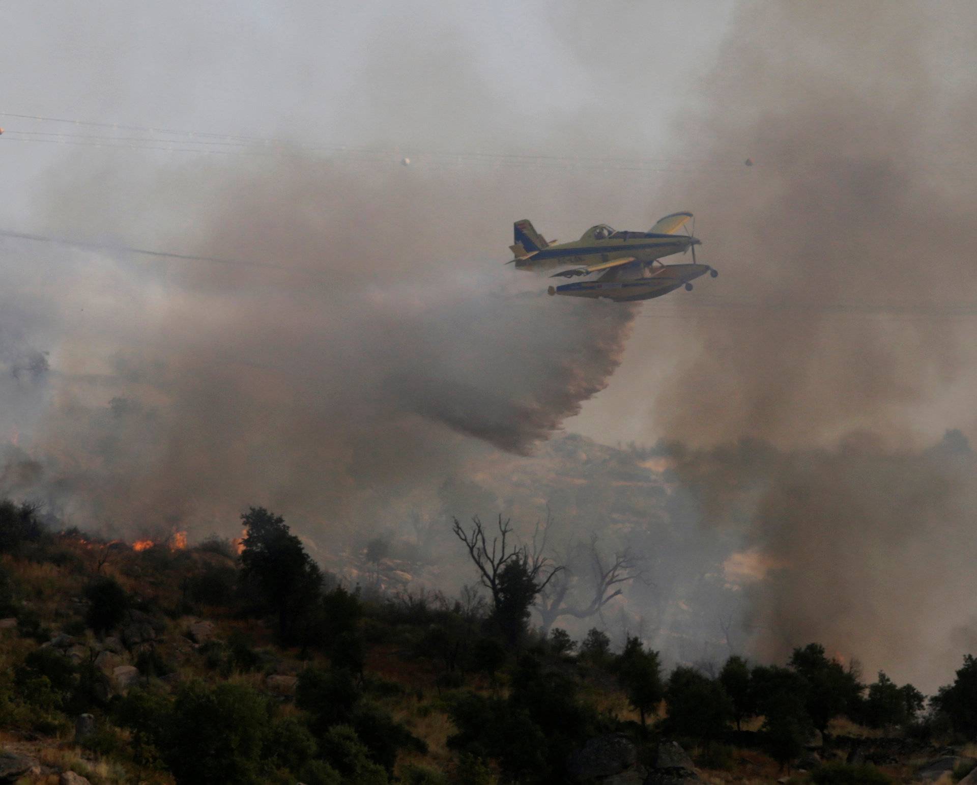 An aircraft drops water over a forest fire near Lagoaca