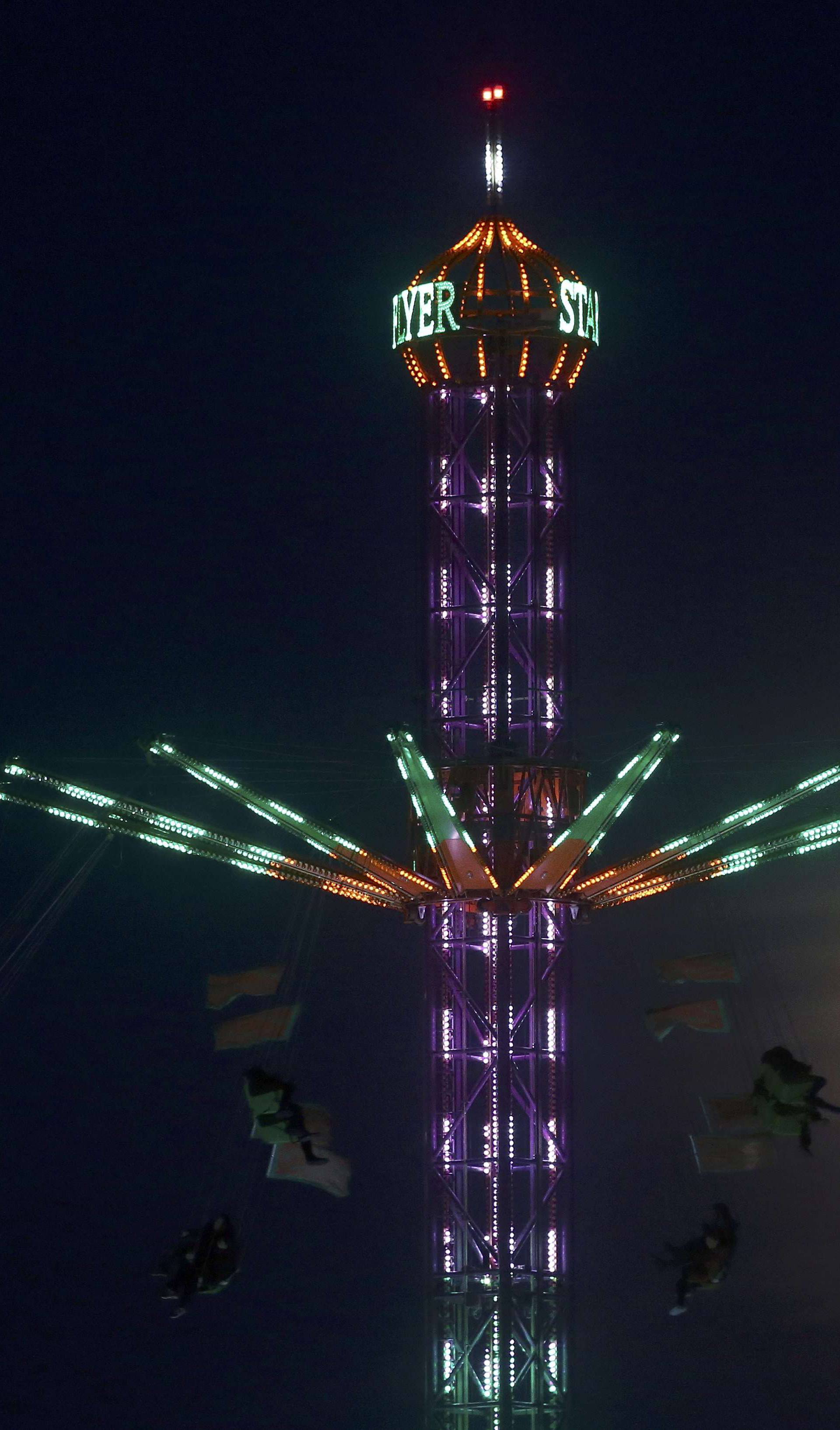 People on a funfair ride are silhouetted against the moon a day before the "supermoon" spectacle, in London