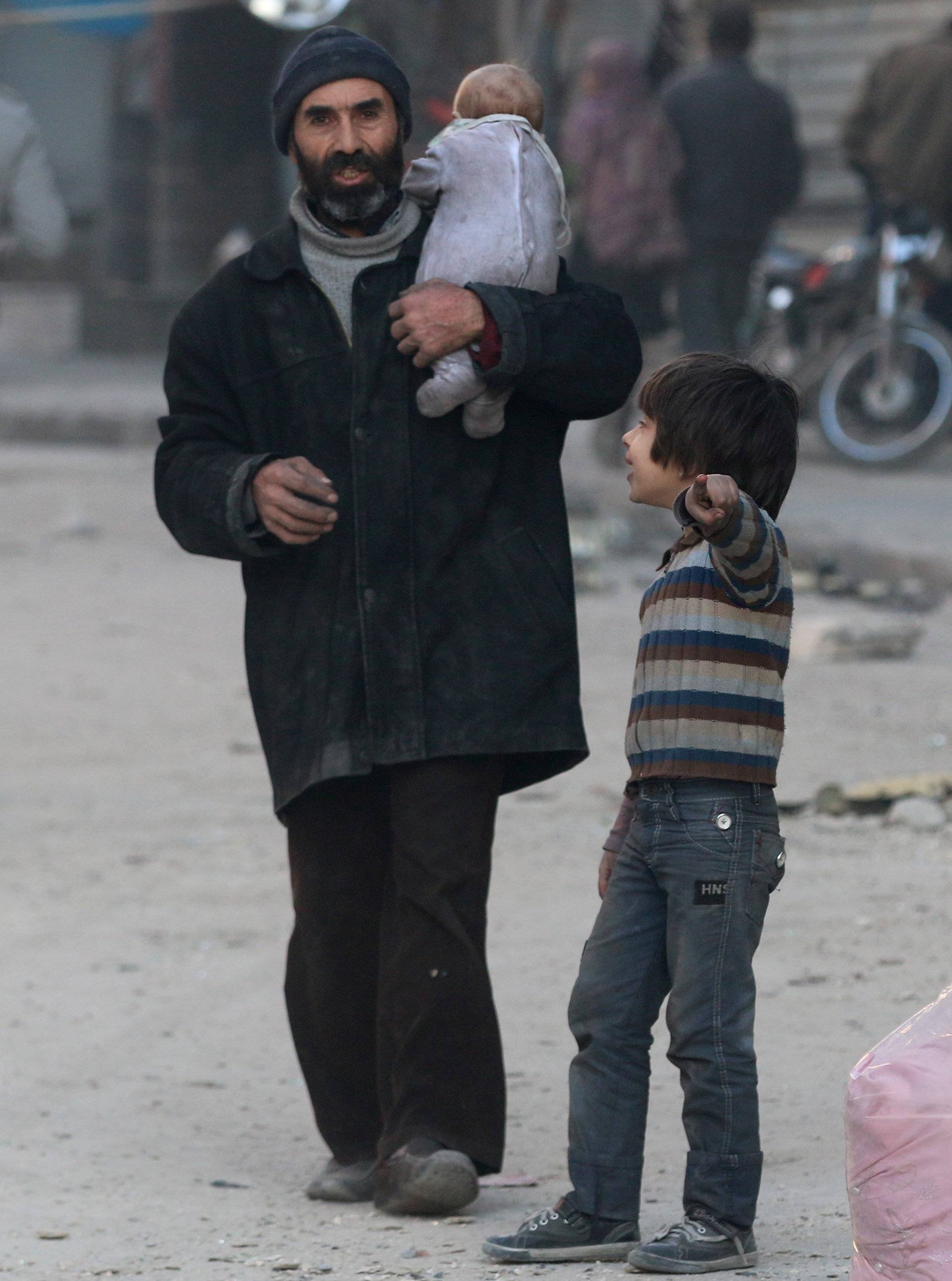 A boy gestures as he chats with his father in the rebel-held besieged al-Shaar neighborhood of Aleppo