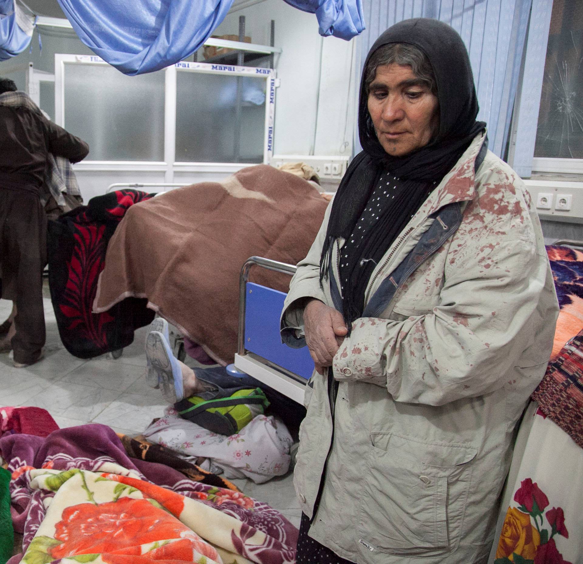 A woman stands next to wounded people as they are treated following an earthquake in Sarpol-e Zahab county in Kermanshah