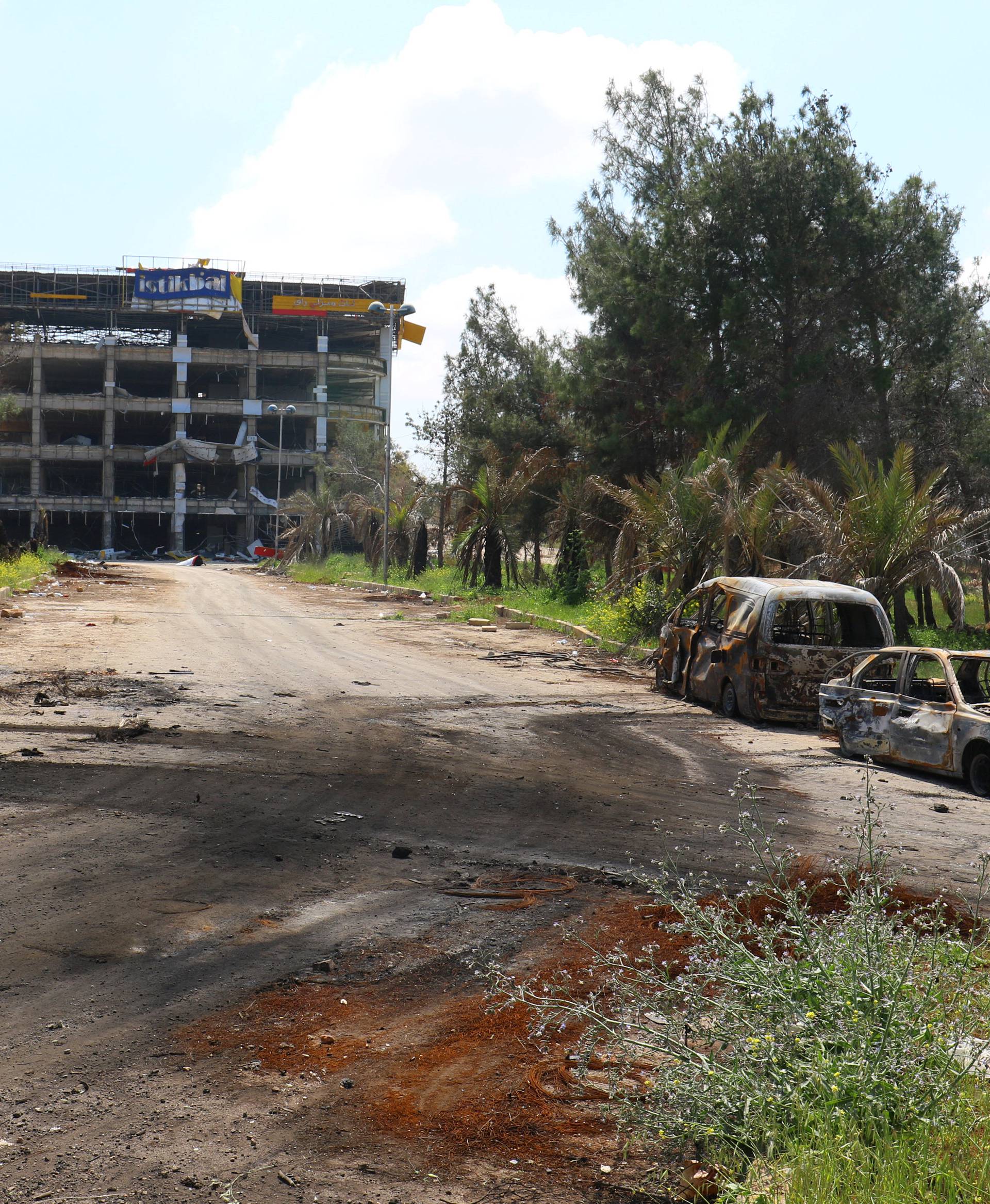 Damaged vehicles are seen after an explosion yesterday at insurgent-held al-Rashideen