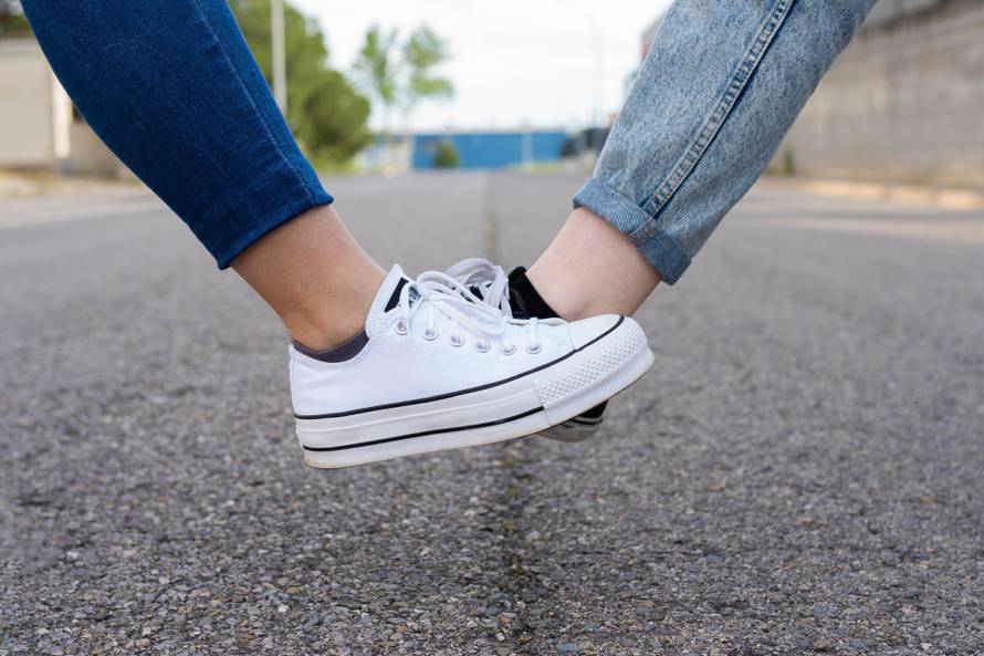 Foot tap. New novel greeting to avoid the spread of coronavirus. Two women friends meet in a British street. Instead of greeting with a hug or handshake, they touch their feet together instead.