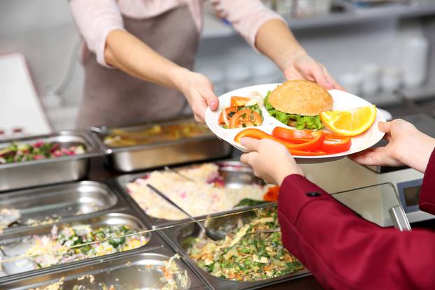 Pleasant,Woman,Giving,Lunch,To,School,Girl,In,Cafeteria