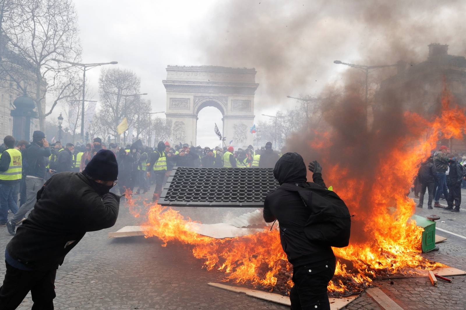 Protesters react next to a burning barricade during a demonstration by the "yellow vests" movement in Paris