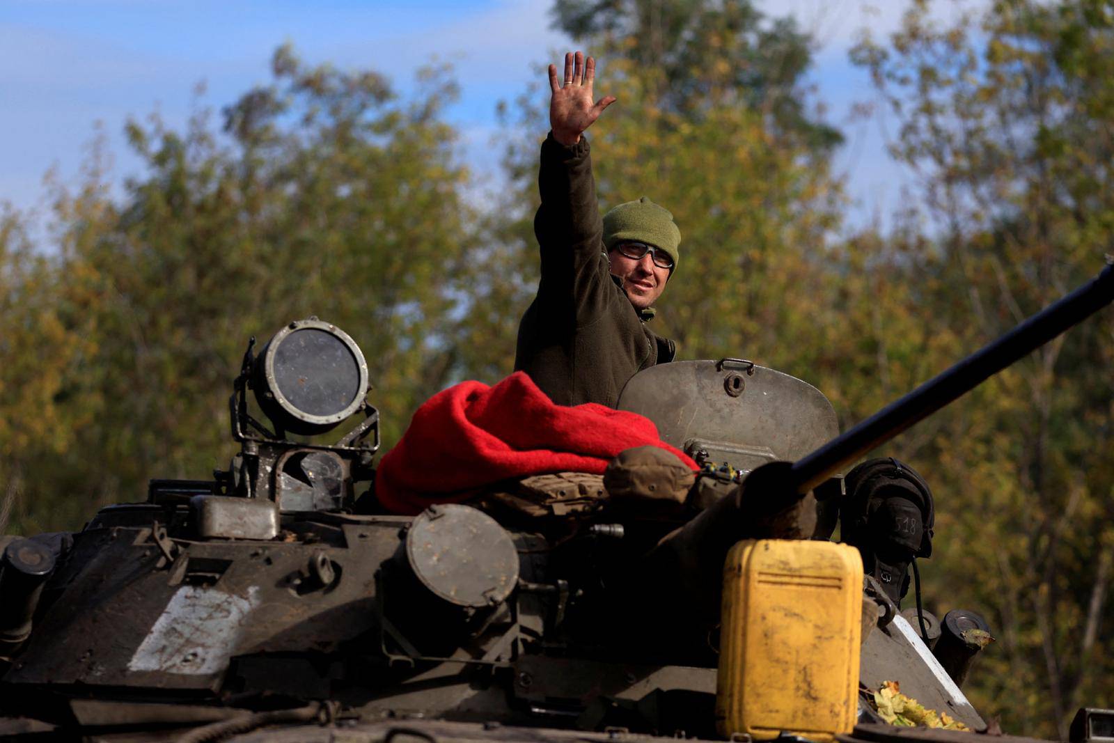 Ukrainian waves as he rides an armoured vehicle outside Bakhmut